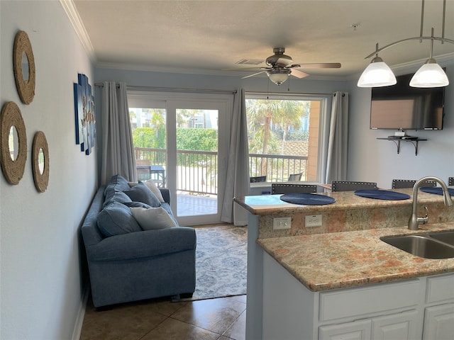 kitchen featuring pendant lighting, ornamental molding, sink, white cabinetry, and ceiling fan