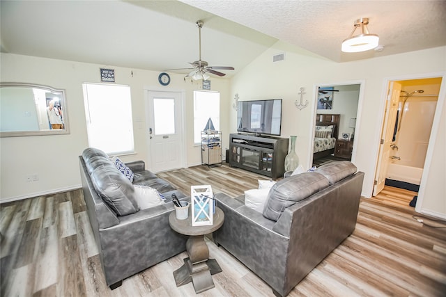 living room with light wood-type flooring, lofted ceiling, a textured ceiling, and ceiling fan