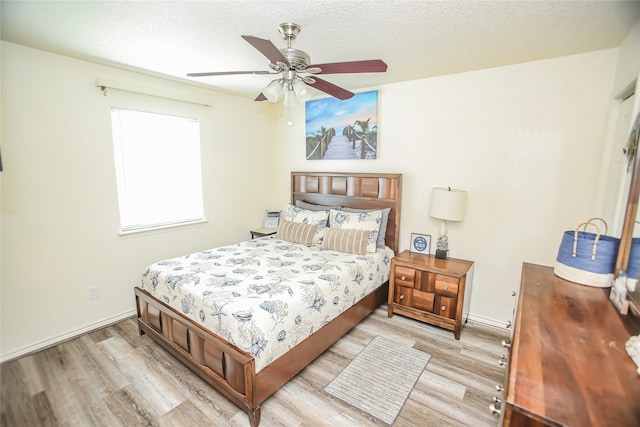 bedroom with a textured ceiling, light hardwood / wood-style floors, and ceiling fan