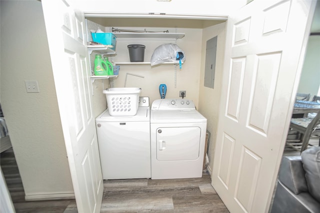 washroom featuring light wood-type flooring, electric panel, and washing machine and clothes dryer