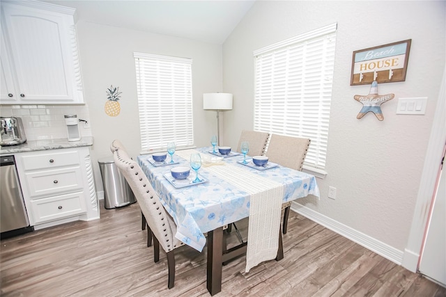 dining room with light hardwood / wood-style flooring and vaulted ceiling