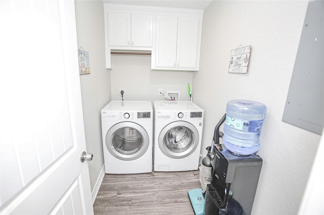 clothes washing area featuring cabinets, light hardwood / wood-style floors, and washer and clothes dryer