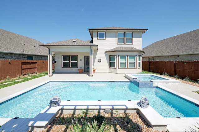 back of property with a swimming pool with hot tub and a patio