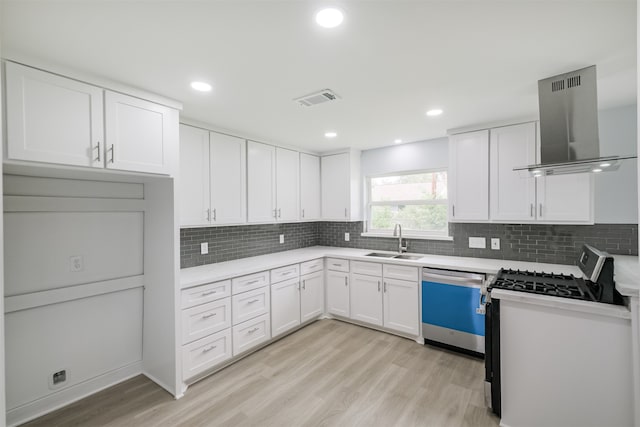 kitchen with wall chimney range hood, appliances with stainless steel finishes, white cabinetry, and sink