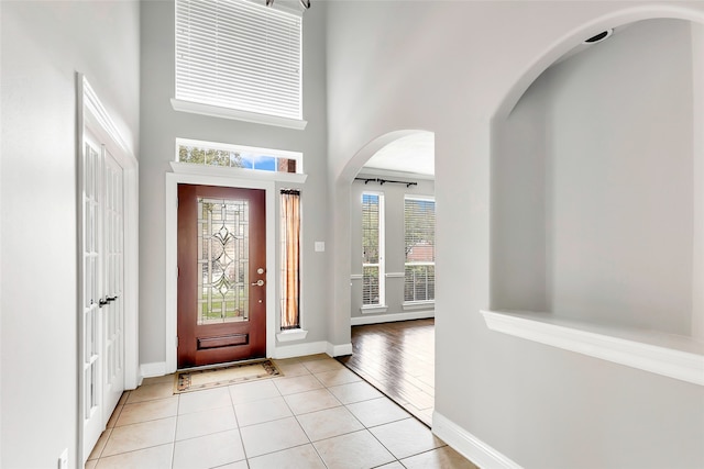 foyer with a towering ceiling and light tile patterned flooring