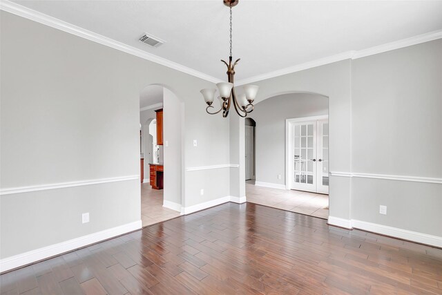 unfurnished room with crown molding, hardwood / wood-style floors, and a notable chandelier