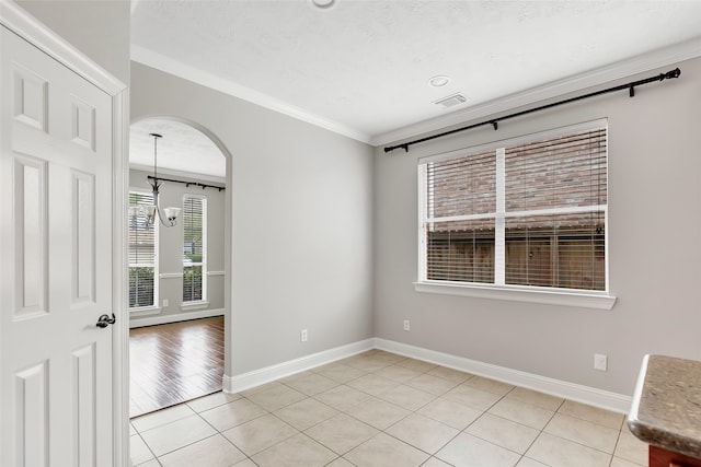 empty room featuring a textured ceiling, a healthy amount of sunlight, ornamental molding, and light hardwood / wood-style floors