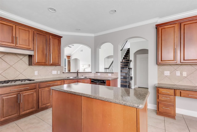 kitchen with appliances with stainless steel finishes, a kitchen island, tasteful backsplash, and sink