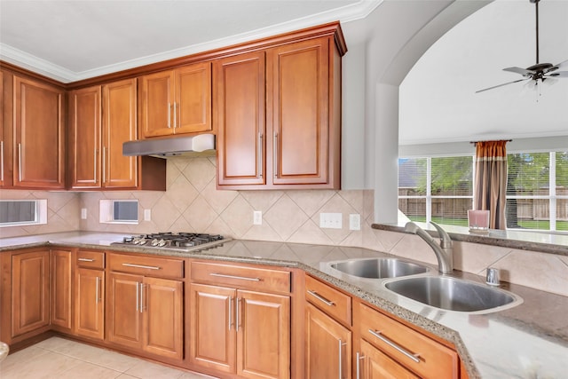 kitchen with ornamental molding, stainless steel gas cooktop, tasteful backsplash, sink, and light stone countertops