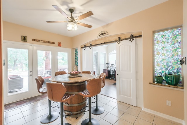 tiled dining room with french doors, ceiling fan, and a barn door