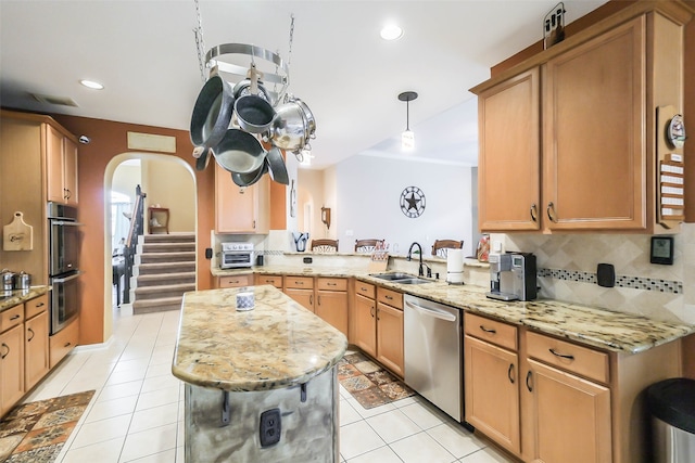 kitchen featuring light tile patterned floors, appliances with stainless steel finishes, light stone counters, sink, and kitchen peninsula