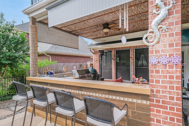 view of patio featuring exterior bar, area for grilling, and ceiling fan