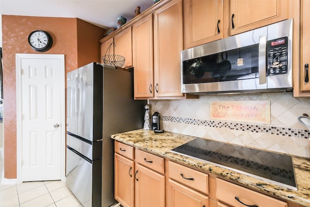 kitchen with appliances with stainless steel finishes, light tile patterned floors, light stone countertops, and decorative backsplash