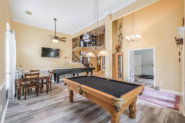 rec room with billiards, ceiling fan with notable chandelier, wood-type flooring, a towering ceiling, and ornamental molding