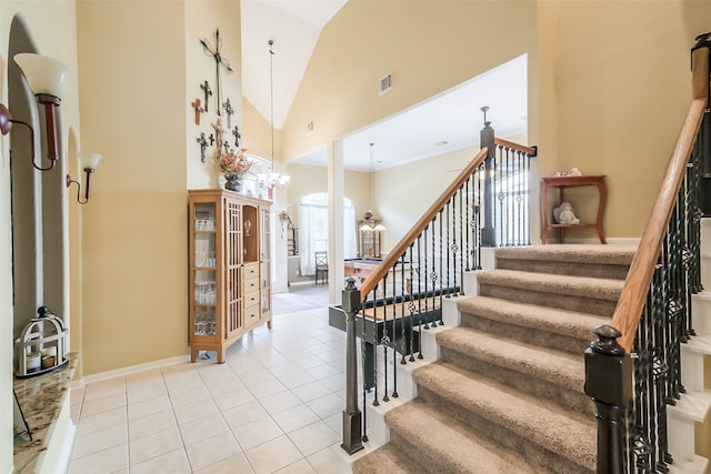 stairway featuring tile patterned flooring, high vaulted ceiling, and a chandelier