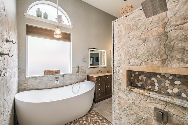 bathroom with tile patterned floors, tile walls, a tub to relax in, and vanity