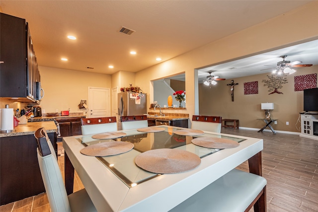 dining area featuring ceiling fan, sink, and light wood-type flooring