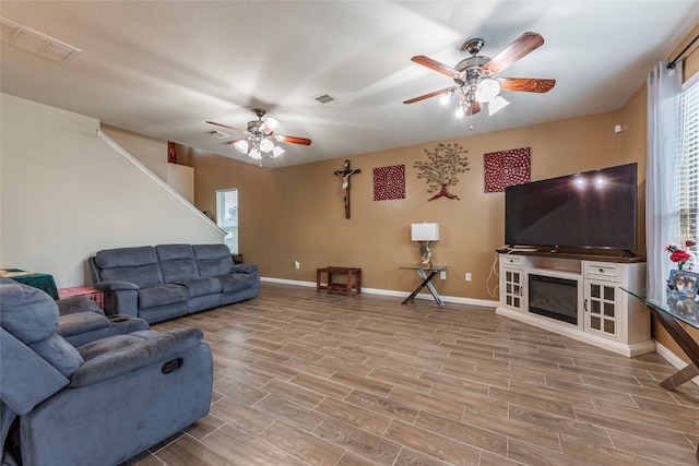 living room featuring light wood-type flooring, a healthy amount of sunlight, and ceiling fan