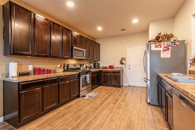 kitchen featuring stainless steel appliances, sink, dark brown cabinetry, and light hardwood / wood-style flooring