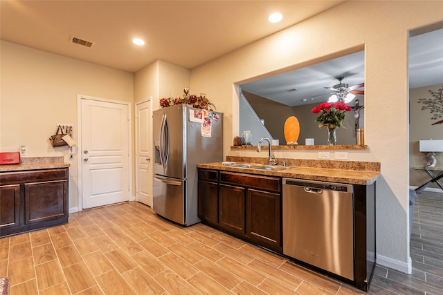 kitchen with dark brown cabinets, light hardwood / wood-style flooring, appliances with stainless steel finishes, sink, and ceiling fan