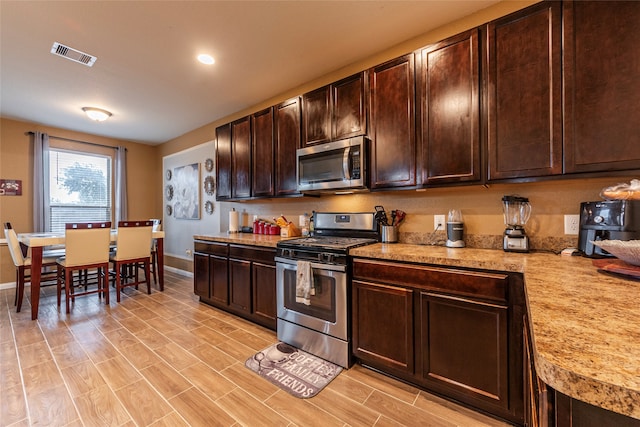 kitchen featuring light wood-type flooring, stainless steel appliances, and dark brown cabinetry