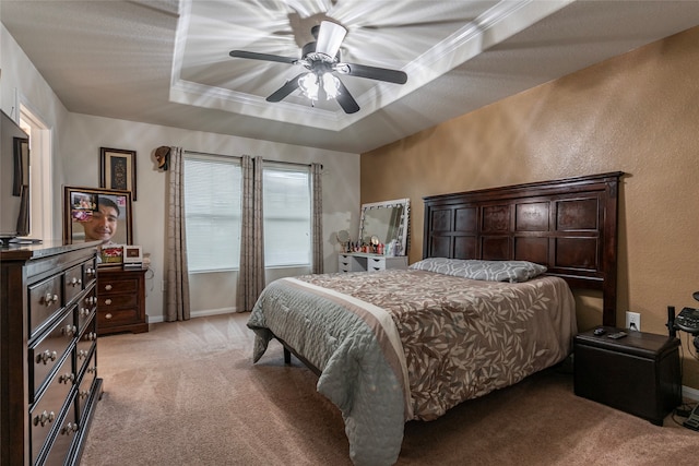 bedroom with carpet flooring, ceiling fan, ornamental molding, and a tray ceiling