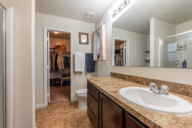 bathroom with a textured ceiling, vanity, walk in shower, toilet, and tile patterned floors