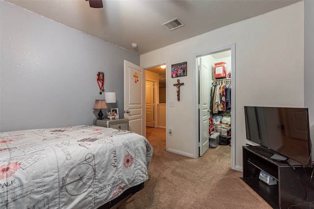 bedroom featuring a walk in closet, ceiling fan, a closet, and carpet