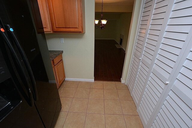 kitchen with decorative light fixtures, dark stone countertops, a chandelier, and light hardwood / wood-style flooring