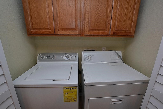 clothes washing area with cabinets and washing machine and dryer