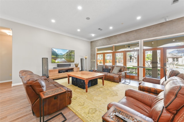 living room with ornamental molding, french doors, and light hardwood / wood-style flooring