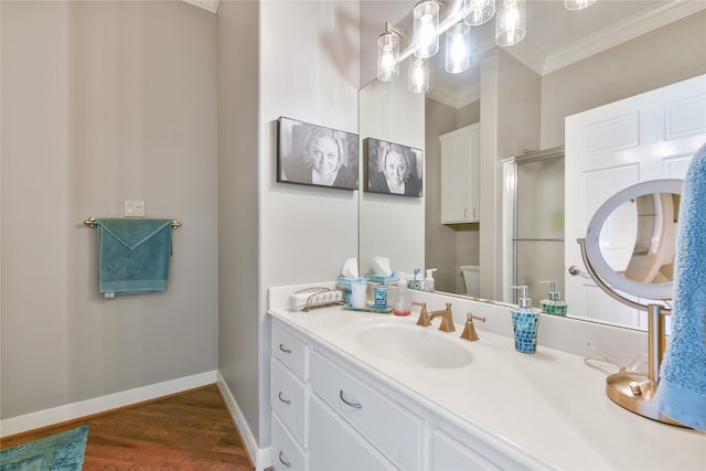 bathroom featuring vanity, a shower with shower door, hardwood / wood-style floors, toilet, and ornamental molding