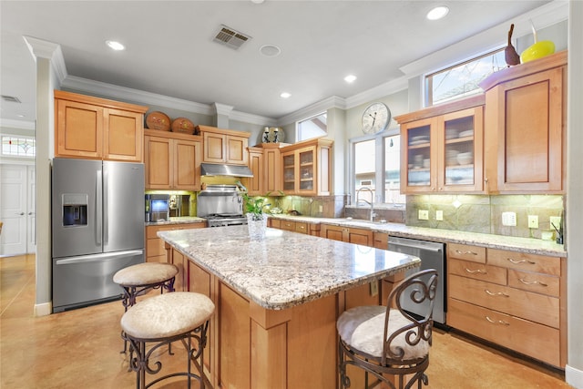 kitchen with a center island, a healthy amount of sunlight, stainless steel appliances, and light stone countertops