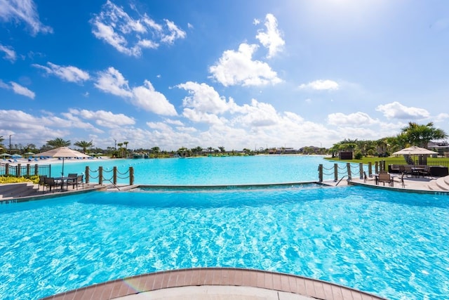 view of swimming pool with a water view and a patio area