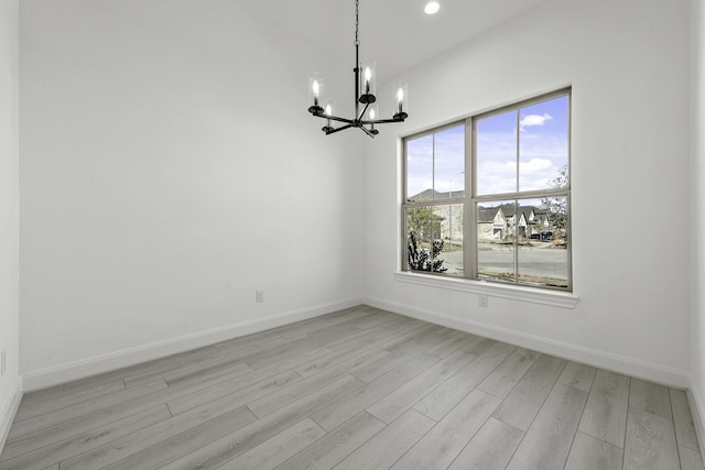 empty room featuring an inviting chandelier and light wood-type flooring