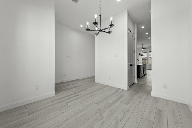 unfurnished living room with ceiling fan with notable chandelier and light wood-type flooring