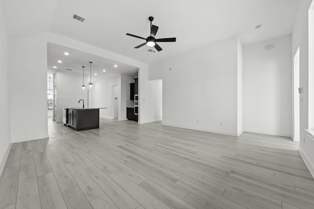 unfurnished living room with sink, ceiling fan, and light hardwood / wood-style flooring