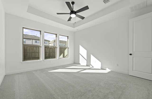 unfurnished room featuring ceiling fan, a raised ceiling, and carpet floors