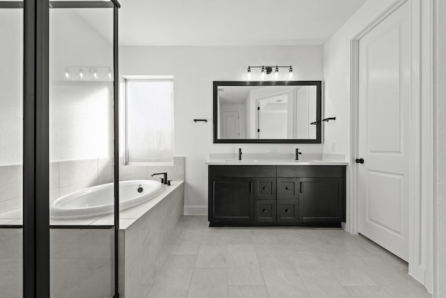 bathroom featuring tile patterned flooring, vanity, and tiled bath