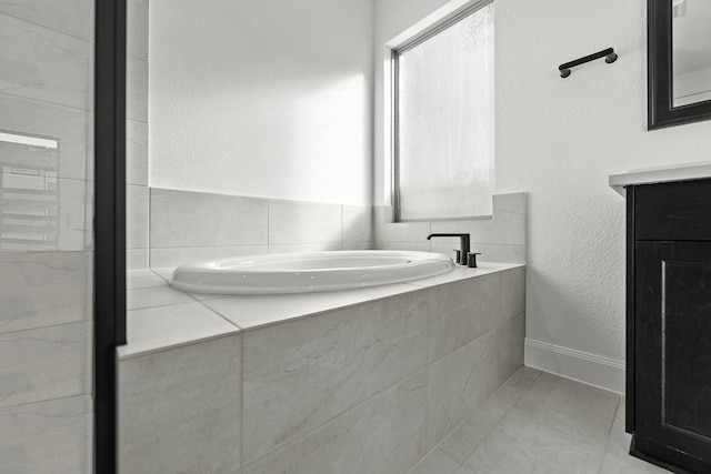 bathroom with tile patterned floors, vanity, and tiled bath