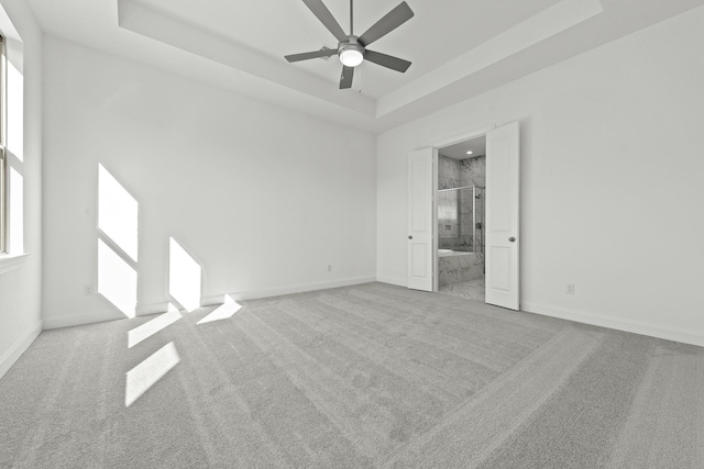 carpeted spare room featuring ceiling fan and a tray ceiling