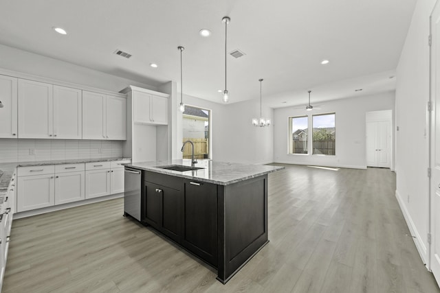 kitchen with white cabinetry, an island with sink, sink, and backsplash