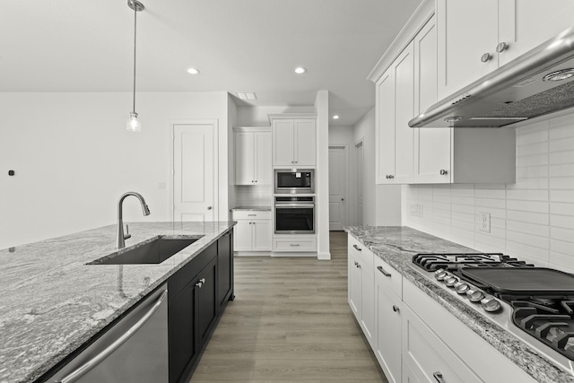 kitchen with appliances with stainless steel finishes, hardwood / wood-style floors, white cabinetry, sink, and hanging light fixtures