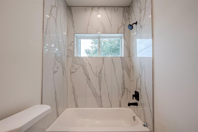 bathroom with tiled shower / bath and toilet