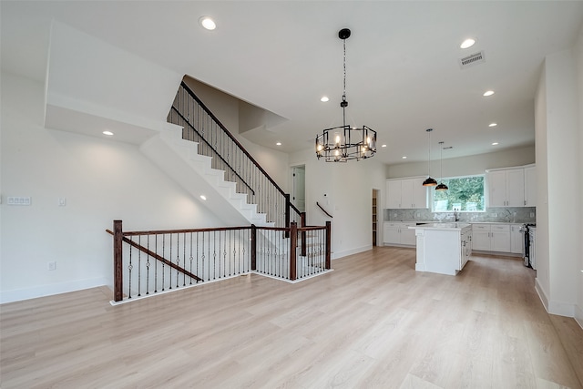 kitchen featuring a chandelier, a kitchen island, light hardwood / wood-style flooring, hanging light fixtures, and white cabinetry