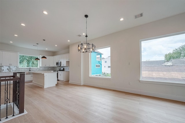 kitchen featuring hanging light fixtures, white cabinets, light wood-type flooring, and a kitchen island