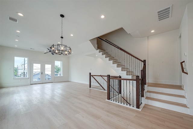 stairs with french doors, hardwood / wood-style floors, and a notable chandelier