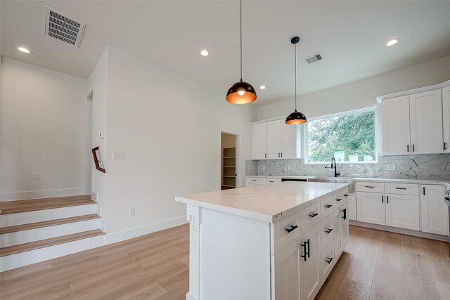 kitchen with pendant lighting, white cabinets, light hardwood / wood-style flooring, and a center island