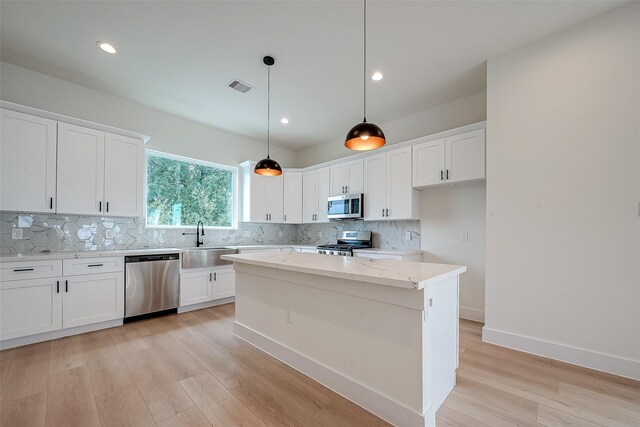 kitchen featuring a kitchen island, pendant lighting, white cabinetry, and stainless steel appliances