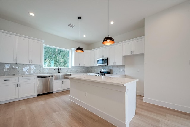 kitchen with decorative light fixtures, white cabinets, stainless steel appliances, and a kitchen island